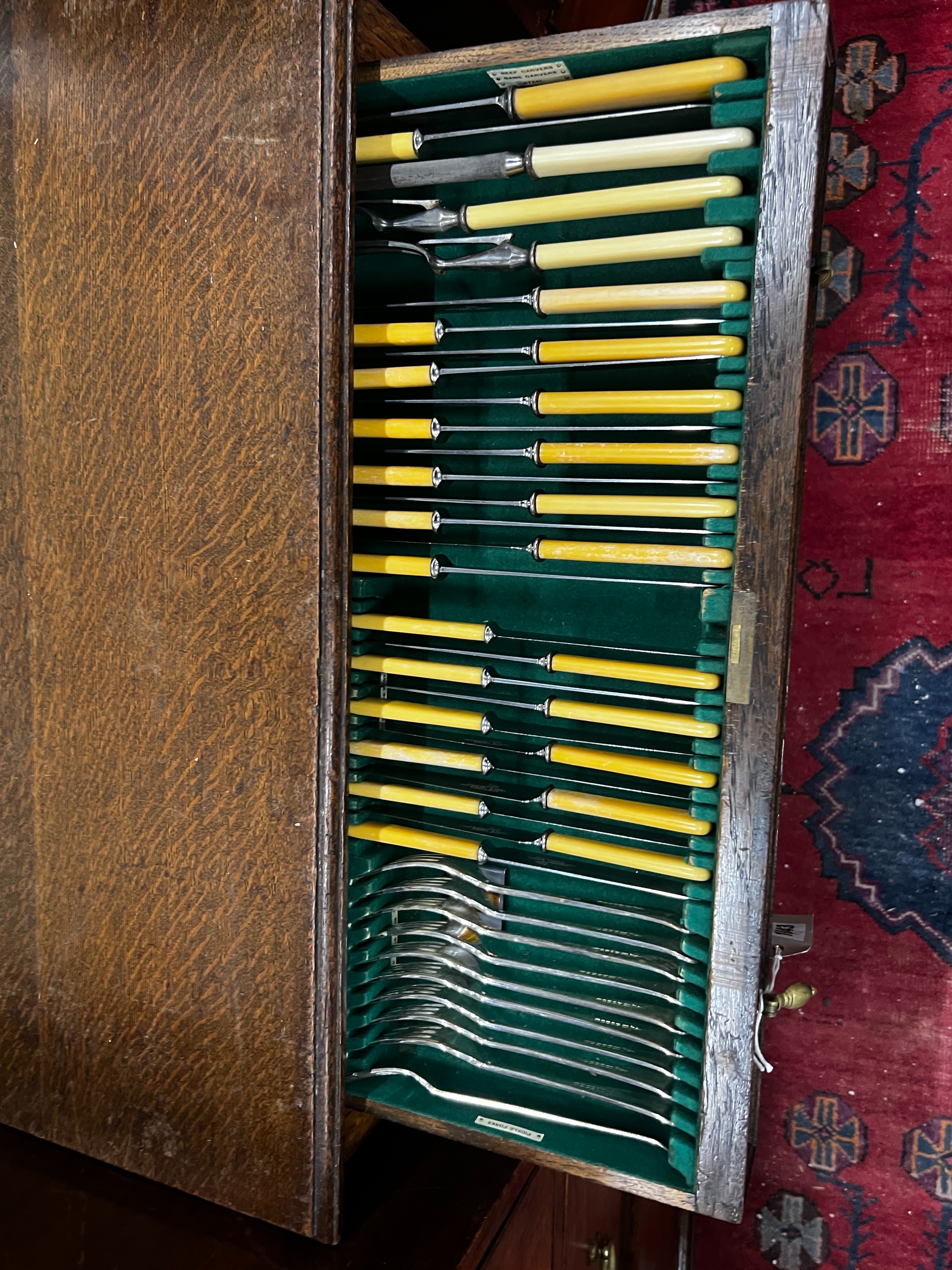 A part canteen of Walker & Hall silver plated Old English pattern cutlery, contained in an oak standing two drawer chest, width 68cm, depth 47cm, height 77cm